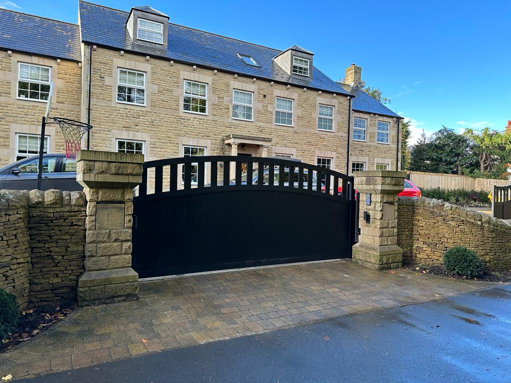 Black aluminium gate by TFS Gates installed outside a large beige house